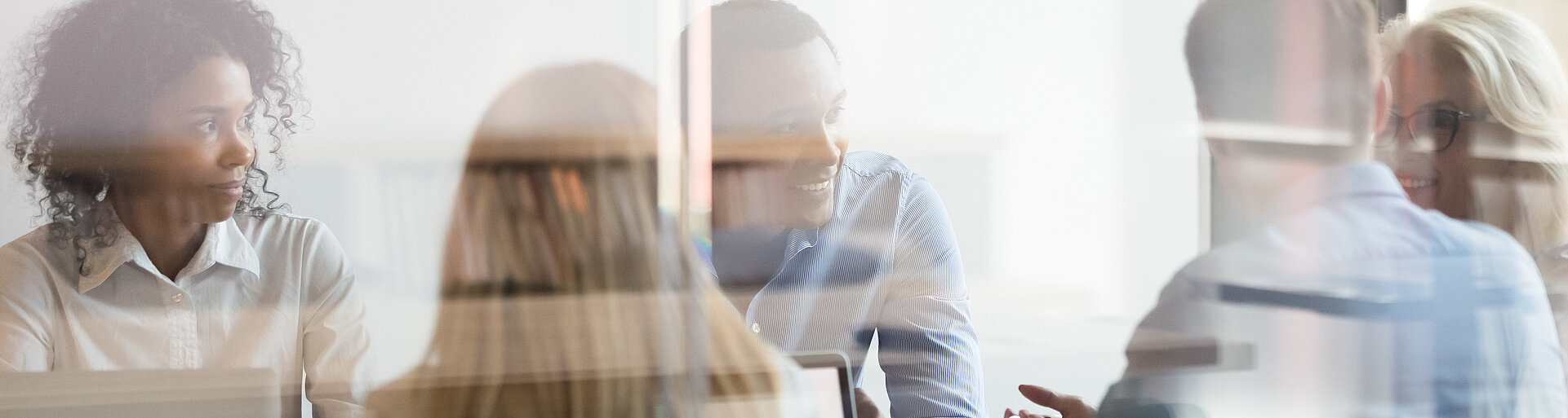 Multicultural employees talking at team meeting sit at conference table