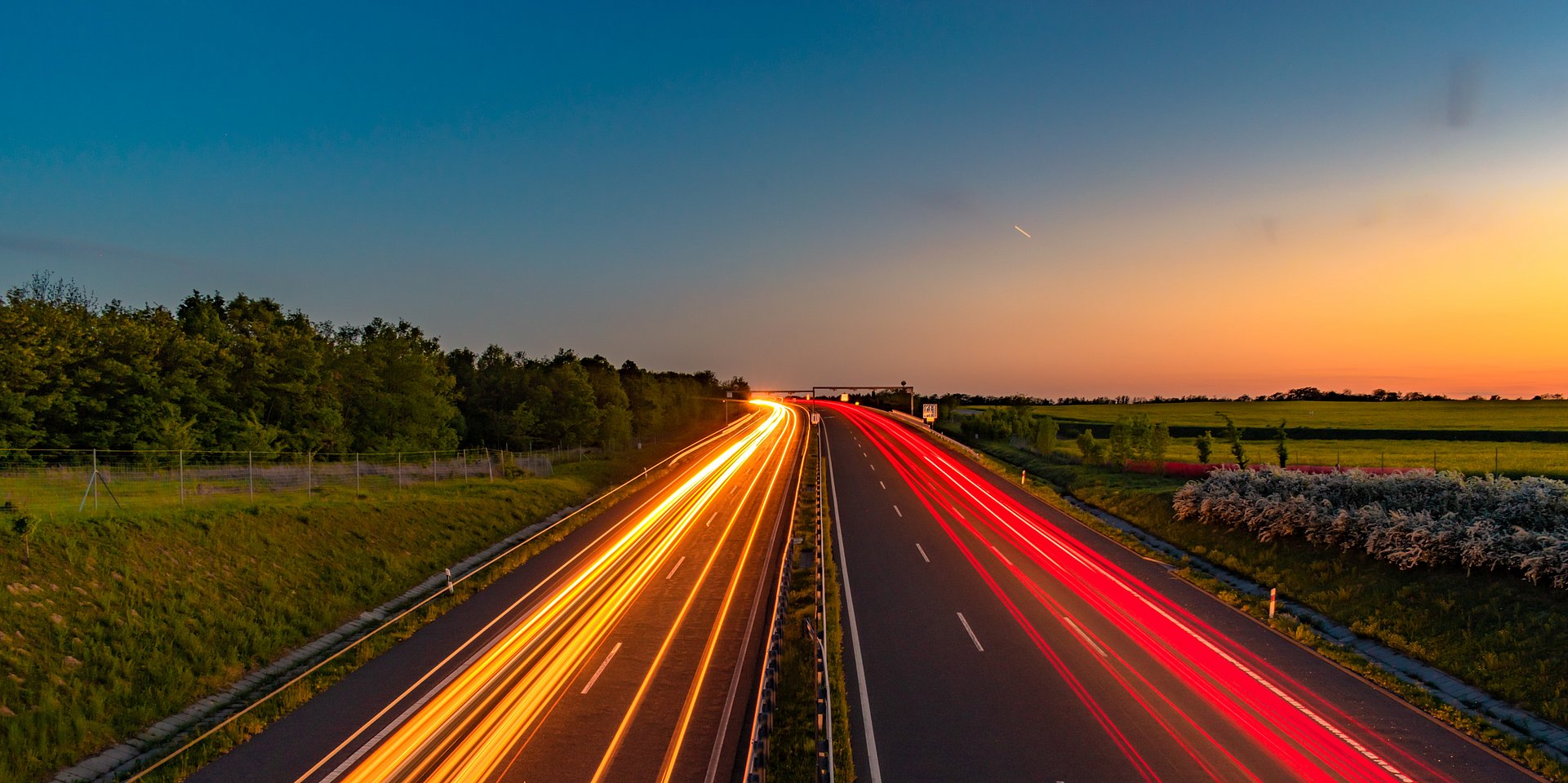 Road through countryside at sunset with streaks of light from headlights Road through countryside at sunset with streaks of light from headlights